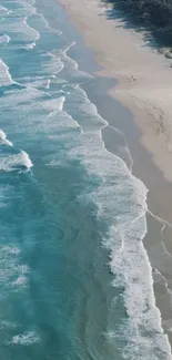 Aerial view of turquoise ocean waves hitting a sandy beach, with a forest backdrop.