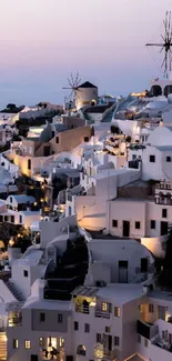 Stunning sunset view of Santorini's white buildings and iconic windmills.