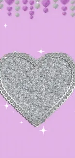 Silver glitter heart on pink background.