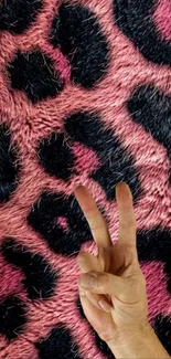 Pink animal print wallpaper with peace sign hand gesture.