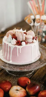 Pink cake topped with macarons and fruit on a decorative table.