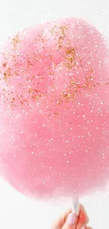 Pink cotton candy with golden sprinkles, handheld.