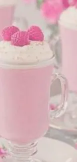 Pastel pink milkshake with raspberries in glass.