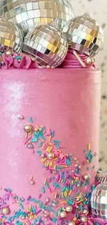 Pink cake with disco balls and sprinkles on white background.