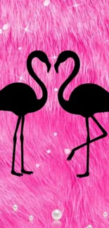 Two flamingos on pink fur background forming a heart.