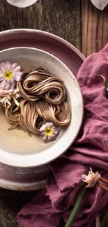 Artistic noodles with flowers on a pink plate, vibrant and serene.