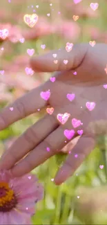 Hand touching pink flower with floating hearts in nature scene.