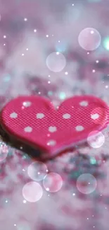 Pink heart on glittery surface with sparkling highlights.