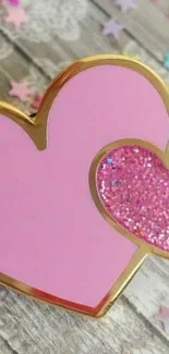 Two intertwined pink hearts with glitter on a wooden background.