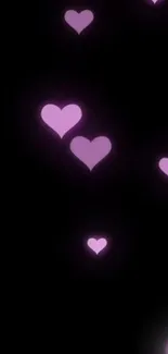 Pink hearts glowing on a black background, creating a romantic mobile wallpaper.