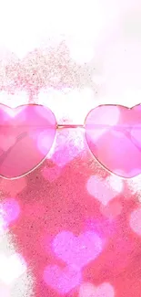 Heart-shaped pink sunglasses with a pink powder background.