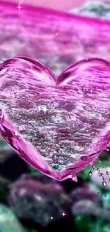 Heart-shaped water drop with a pink hue and rocky background.