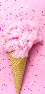 Pink ice cream cone on pink background with colorful sprinkles.