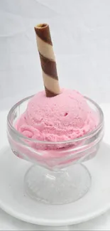 Pink ice cream with wafer in glass dish.