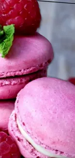 Pink macarons with raspberries and mint leaves on display.