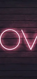 Pink neon love sign on dark wooden background.