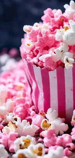 Pink and white popcorn in a striped container.