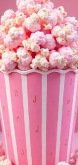Pink popcorn in a striped container on pink background.