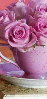 Pink tea cup with roses on a table.