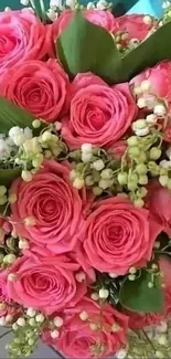 Close-up of a vibrant pink rose bouquet with lush greenery and white blossoms.