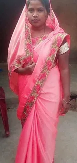 Woman in a bright pink sari standing outdoors.