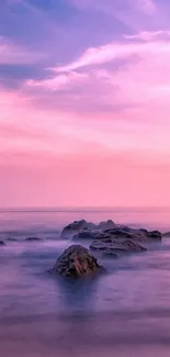 Pink sunset over ocean with rocks in tranquil scene.