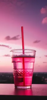 Vibrant pink drink with sunset background.