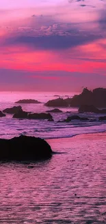 A captivating pink sunset over the ocean with rocky silhouettes.