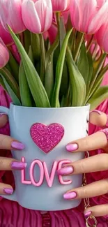 Pink tulips in heart-themed mug with love inscription.