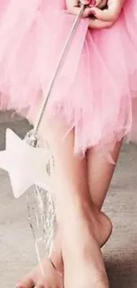 Pink tulle skirt with fairy wand on concrete floor.