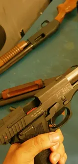 Close-up view of a pistol and rifle on a table.