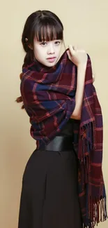 Woman wearing a plaid scarf with neutral beige background.