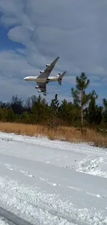 Airplane flying over a snowy forest landscape with a cloudy sky.