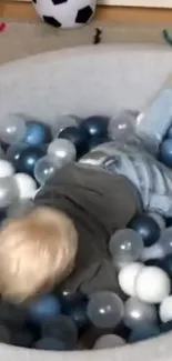 Child enjoying playtime in a cozy ball pit with colorful balls.