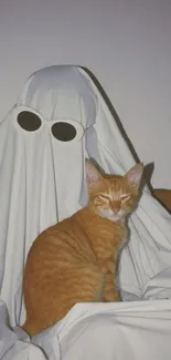 Orange tabby cat sitting beside ghost costume in whimsical setting.