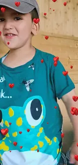 Child in teal T-shirt with red hearts, smiling.