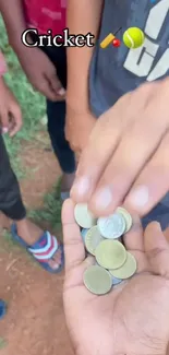 Children exchanging coins while playing cricket outdoors.