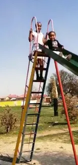 Children playing on a brightly colored slide at the park under a blue sky.