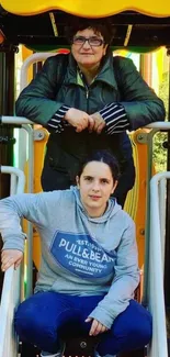 Two people enjoying a playful park day on a vibrant playground structure.