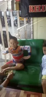 Two kids playing on a green couch with a casual background.