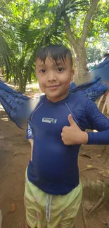 Child smiling and enjoying the outdoors, wearing a blue shirt and surrounded by nature.