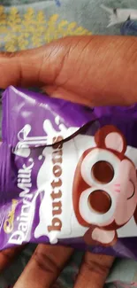 Hand holds a purple snack pack with a cute monkey design.