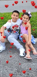 Siblings sitting together on a curb outdoors.