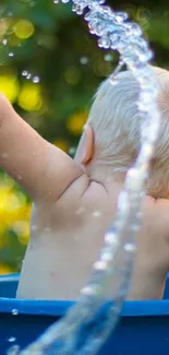 Child splashing water in blue bucket outdoors.