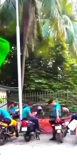 Police officers gathered on motorcycles by lush greenery.