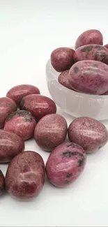 Polished red gemstones in a bowl on white background.