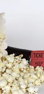 Popcorn spilling with a red movie ticket on a white background.