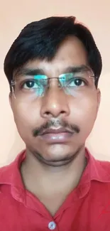 Portrait of a person wearing glasses and a red shirt on a neutral background.