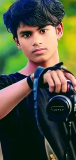 Young man holding a camera in natural, green setting.