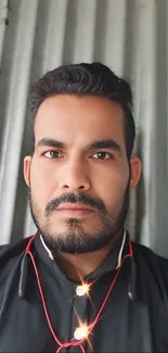 Man in black shirt with metallic background.